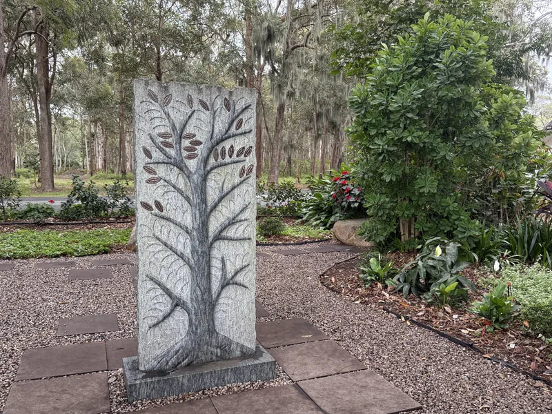 Close view of the carved branching design of the memorial stone with its engraved leaf plaques`