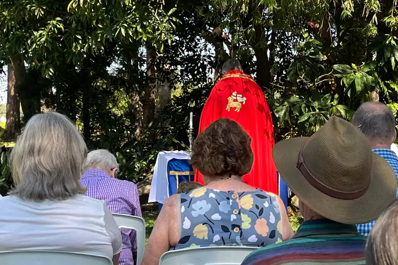Congregation seated for outdoor worship in the grounds of The Abbey Church.