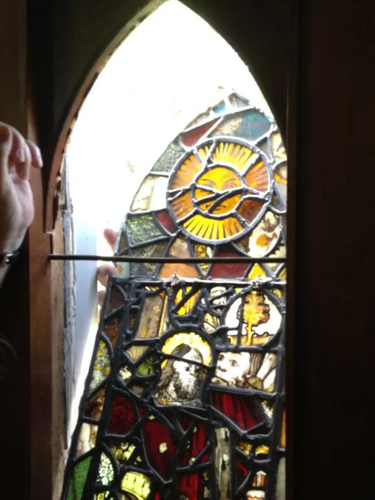 Stained Glass Roundel Being Removed From An Abbey Church Window Hands beside a leaded stained glass panel in a lancet window opening at The Abbey Church